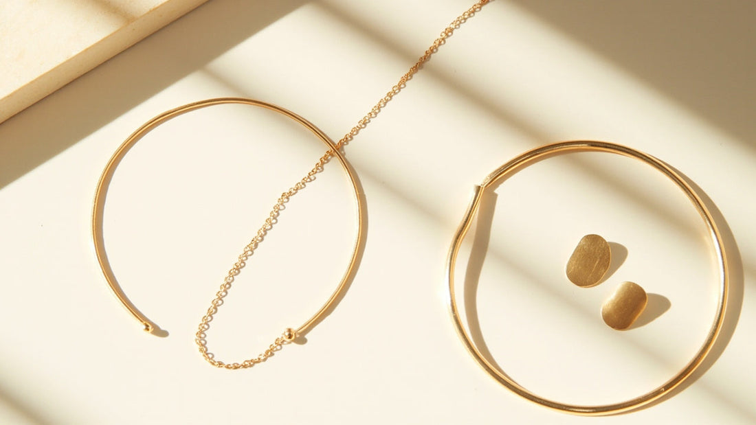 minimalist jewelry flat lay with gold necklace earrings and bracelet on linen
