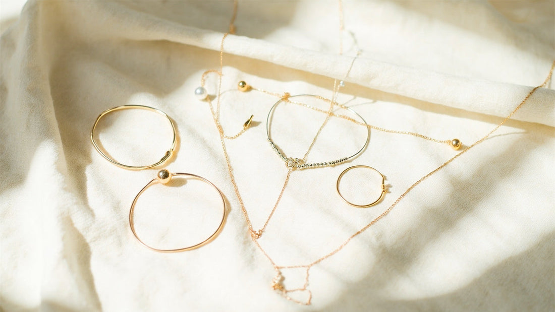 modern minimalist jewelry displayed on linen in soft natural light, gold accents visible