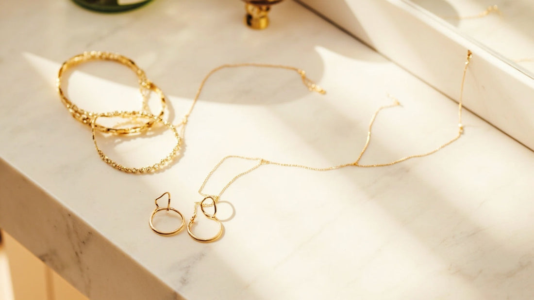 minimalist gold jewelry arranged on a bright marble vanity in soft morning light