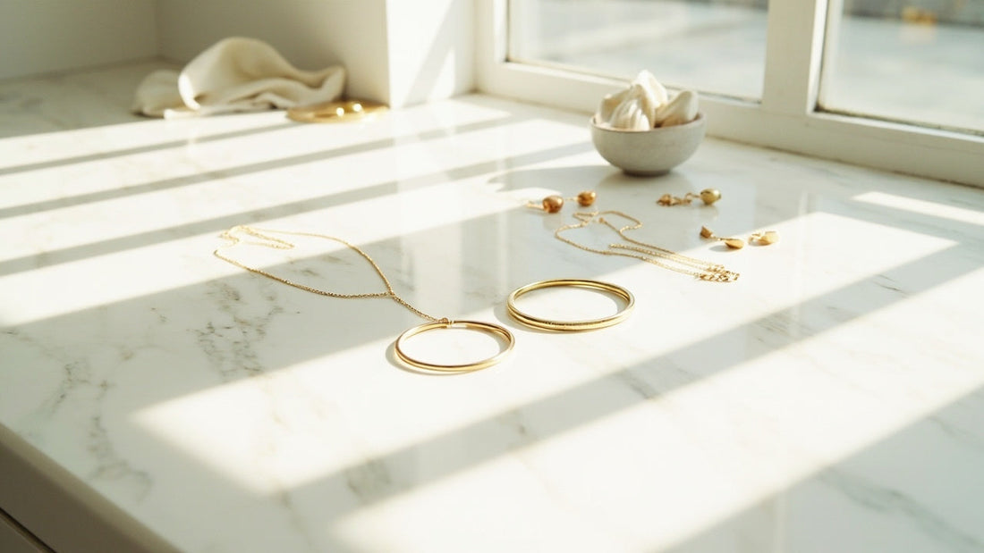 minimal gold jewelry arranged on a marble vanity in soft morning light